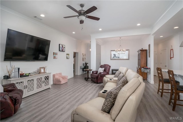 living room featuring hardwood / wood-style floors, ceiling fan with notable chandelier, and ornamental molding