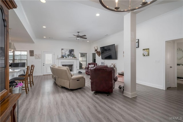 living room with hardwood / wood-style floors, ceiling fan with notable chandelier, and ornamental molding