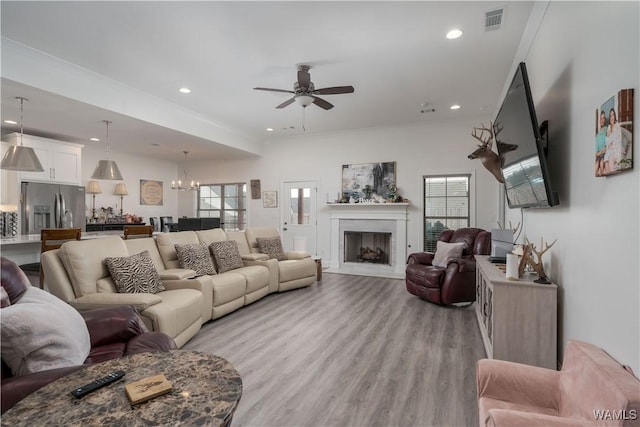 living room with ceiling fan with notable chandelier and light wood-type flooring