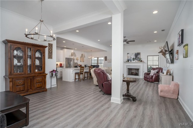 living room featuring crown molding, ceiling fan with notable chandelier, and light hardwood / wood-style flooring