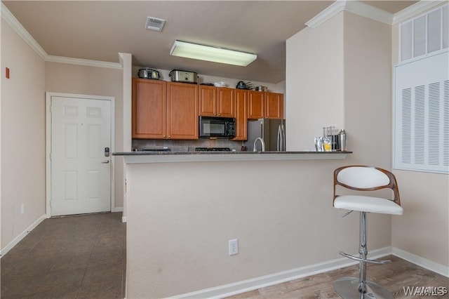 kitchen with crown molding, stainless steel fridge, kitchen peninsula, and tasteful backsplash