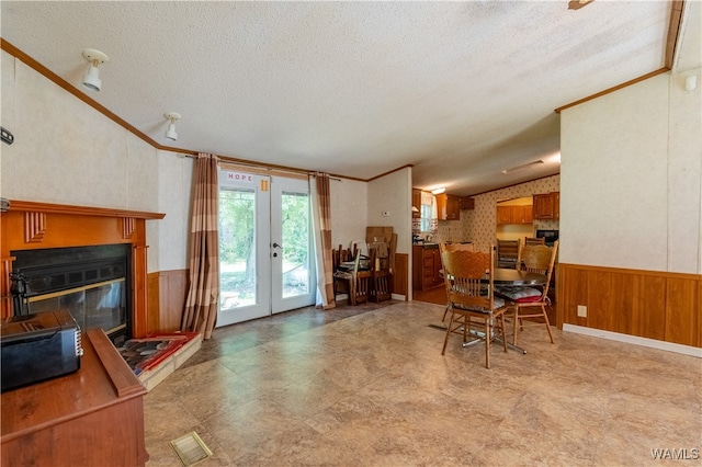 dining area with a textured ceiling, french doors, crown molding, and vaulted ceiling