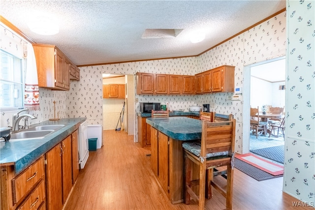 kitchen with sink, crown molding, vaulted ceiling, a textured ceiling, and light wood-type flooring