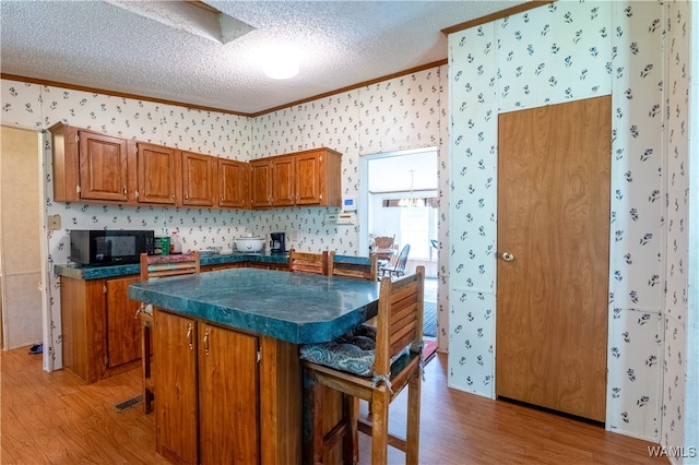 kitchen with a kitchen bar, hardwood / wood-style floors, a textured ceiling, and a center island