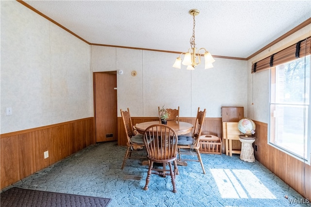 carpeted dining space featuring a wealth of natural light, a textured ceiling, and an inviting chandelier