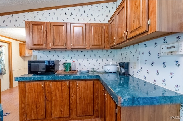 kitchen featuring a textured ceiling, light hardwood / wood-style flooring, lofted ceiling, and ornamental molding