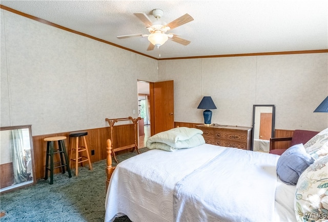 bedroom with ceiling fan, dark carpet, ornamental molding, and a textured ceiling