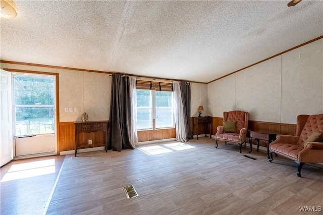 living area featuring a textured ceiling, light hardwood / wood-style flooring, and crown molding