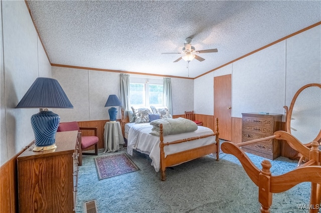 bedroom with ceiling fan, carpet floors, a textured ceiling, wooden walls, and ornamental molding