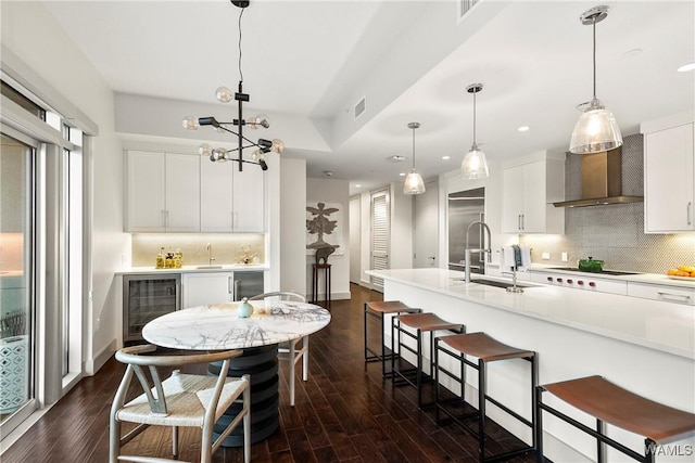 kitchen with white cabinetry, hanging light fixtures, wine cooler, and sink