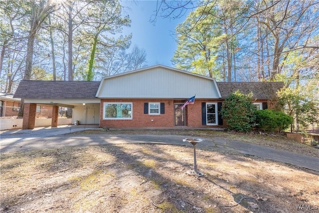 view of front facade with brick siding, driveway, and a shingled roof