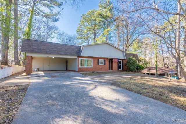 view of front of home featuring a carport, brick siding, driveway, and roof with shingles