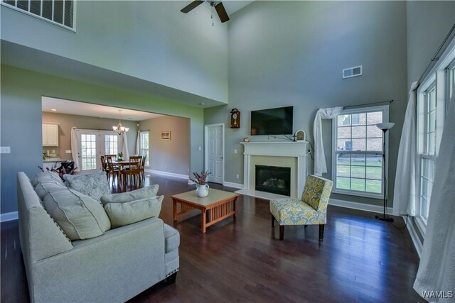 4401 Nicholas Ave, Northport, AL 35473 - living area featuring baseboards, dark wood-style flooring, a towering ceiling, ceiling fan, and a fireplace with flush hearth
