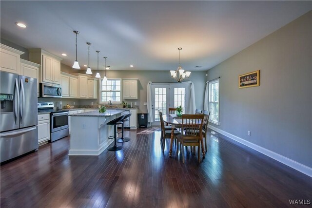 4401 Nicholas Ave, Northport, AL 35473 - kitchen with appliances with stainless steel finishes, a chandelier, a center island, a breakfast bar area, and dark wood-style flooring