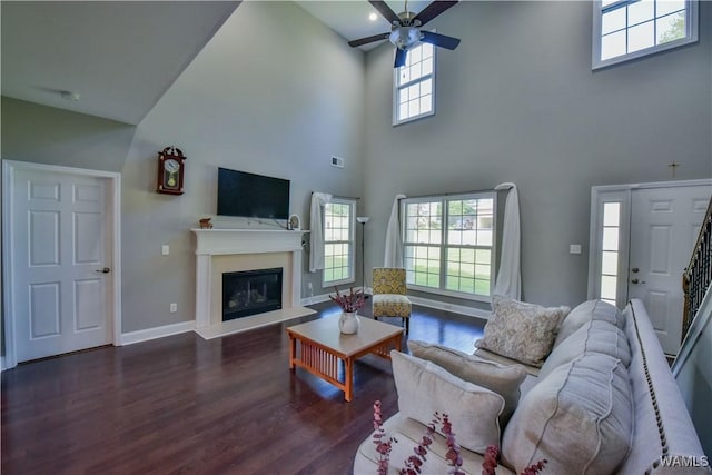 4401 Nicholas Ave, Northport, AL 35473 - living room featuring wood finished floors, a ceiling fan, a towering ceiling, a glass covered fireplace, and baseboards