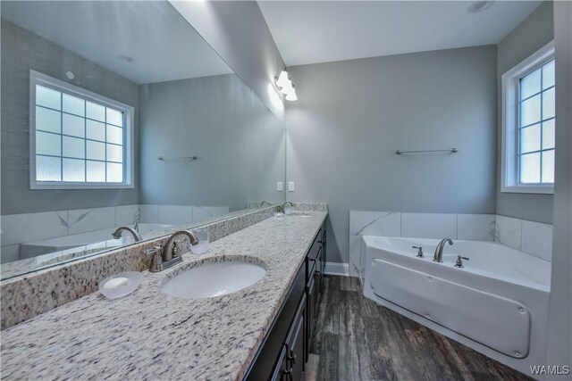4401 Nicholas Ave, Northport, AL 35473 - bathroom featuring wood finished floors, double vanity, a garden tub, and baseboards