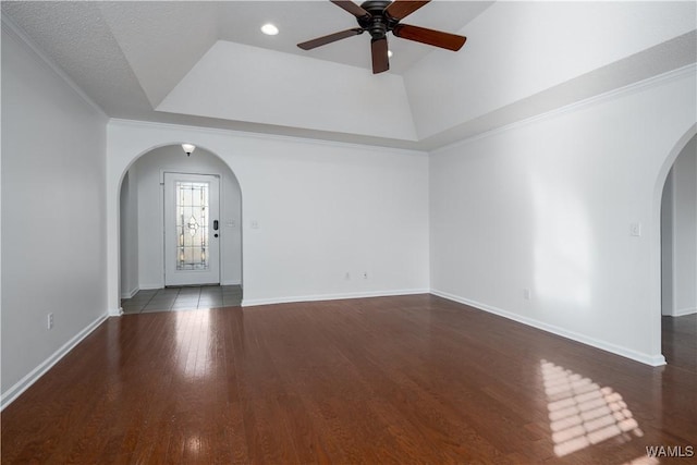 interior space featuring a tray ceiling, ceiling fan, ornamental molding, and dark hardwood / wood-style floors