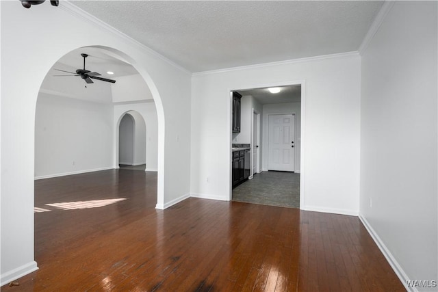 empty room with ceiling fan, dark hardwood / wood-style flooring, ornamental molding, and a textured ceiling