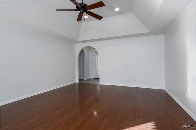 spare room with ceiling fan, dark wood-type flooring, a raised ceiling, a textured ceiling, and ornamental molding