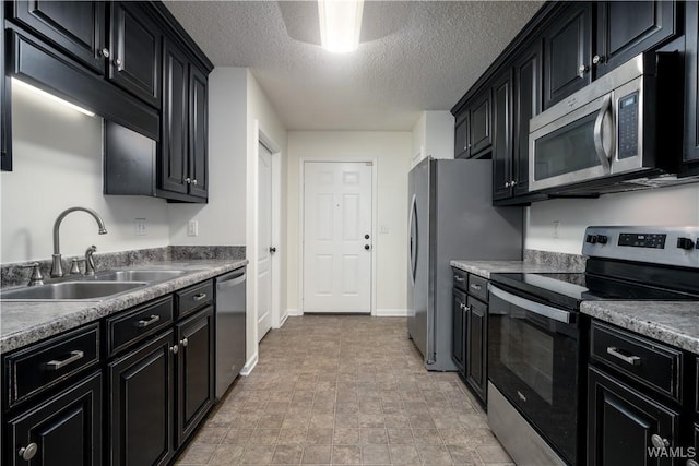 kitchen with a textured ceiling, stainless steel appliances, and sink