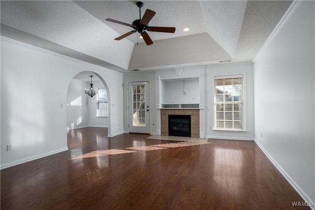 unfurnished living room with ceiling fan with notable chandelier, a textured ceiling, a tray ceiling, a fireplace, and lofted ceiling