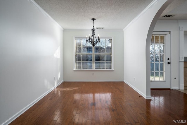 unfurnished dining area with dark hardwood / wood-style floors, ornamental molding, a textured ceiling, and a chandelier