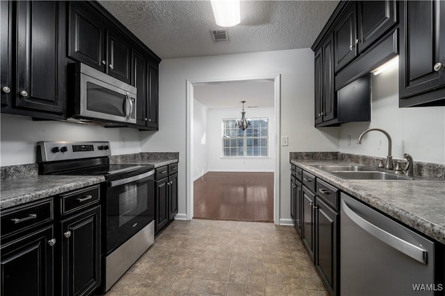 kitchen featuring sink, an inviting chandelier, a textured ceiling, and appliances with stainless steel finishes