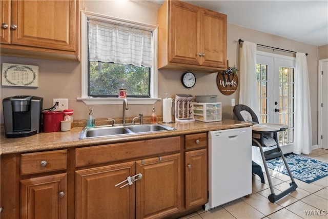 kitchen with plenty of natural light, sink, white dishwasher, and light tile patterned floors