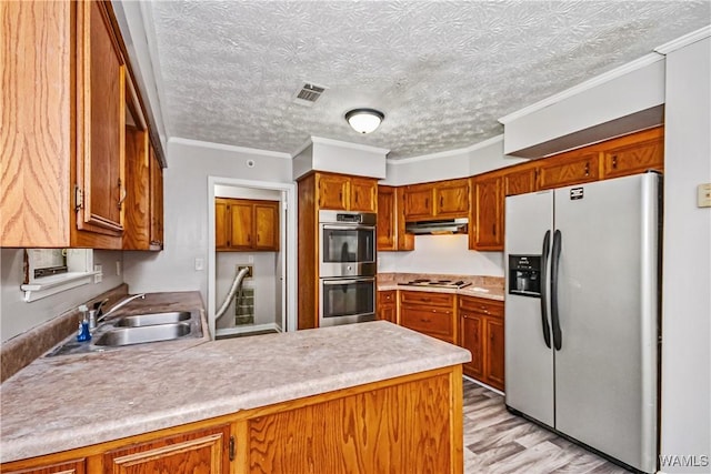 1924 Still Oaks Dr, Montgomery, AL 36117 - kitchen featuring appliances with stainless steel finishes, a peninsula, light wood-type flooring, brown cabinets, and crown molding