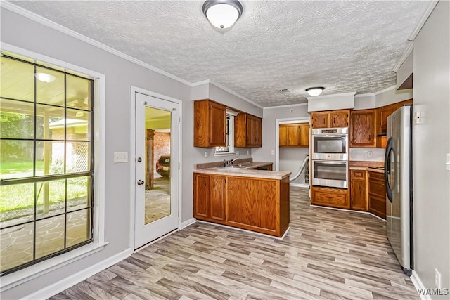 1924 Still Oaks Dr, Montgomery, AL 36117 - kitchen featuring a peninsula, stainless steel appliances, brown cabinets, light wood-style flooring, and ornamental molding