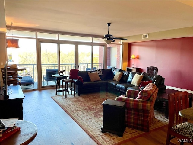 living room with expansive windows, ceiling fan, and wood-type flooring