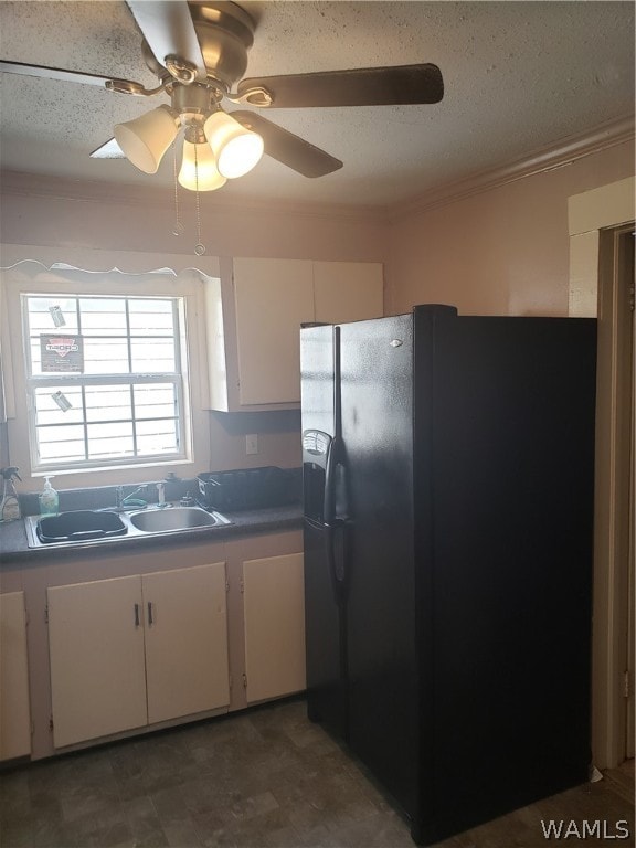 kitchen featuring black fridge, ornamental molding, ceiling fan, sink, and white cabinets