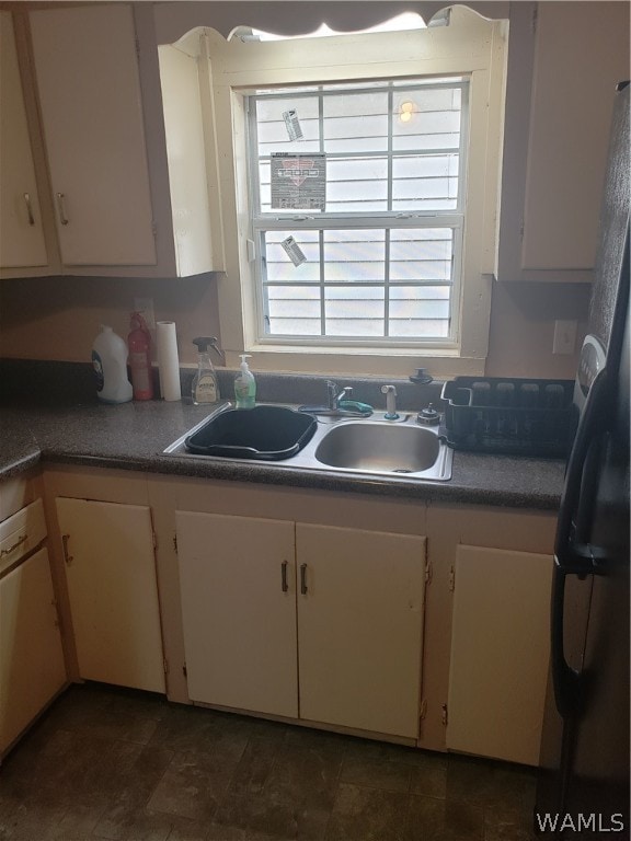 kitchen featuring sink, white cabinets, and fridge