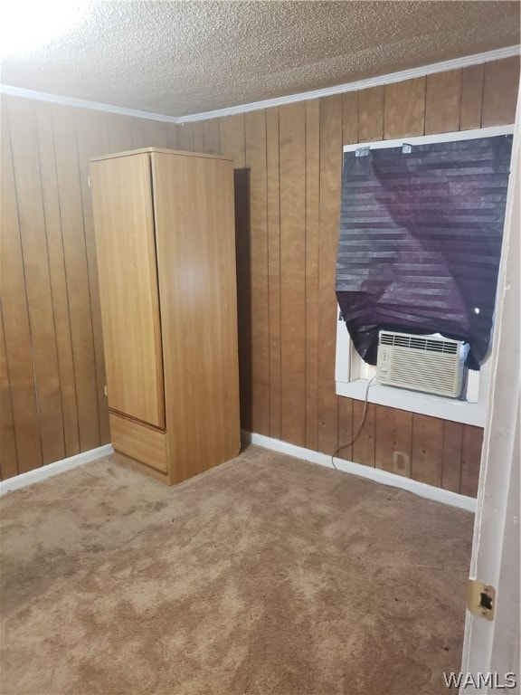 unfurnished bedroom with carpet, wood walls, a textured ceiling, and cooling unit