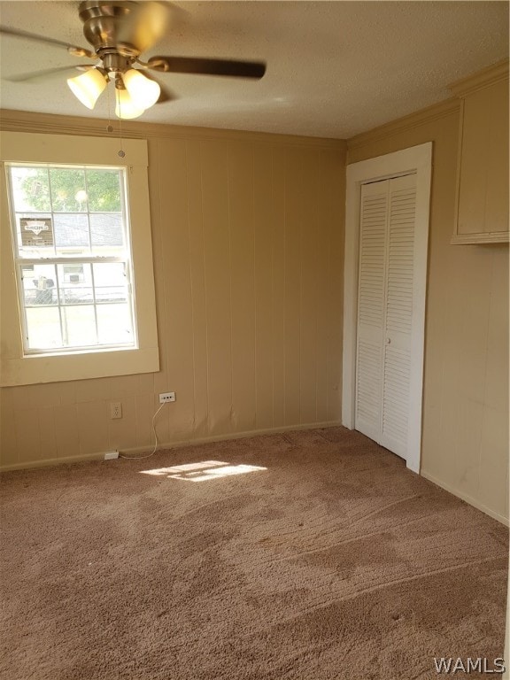 carpeted empty room with ceiling fan, crown molding, and a textured ceiling