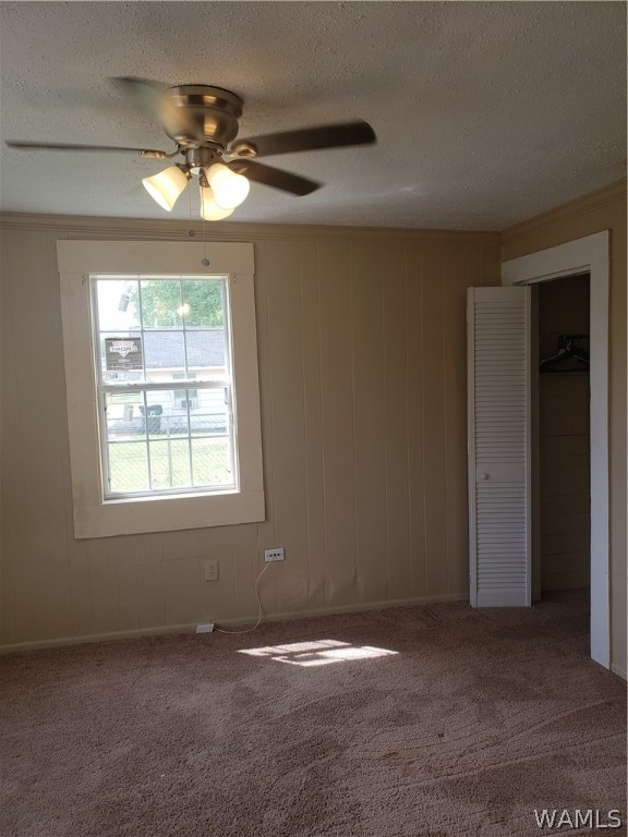 carpeted spare room with a textured ceiling and ceiling fan