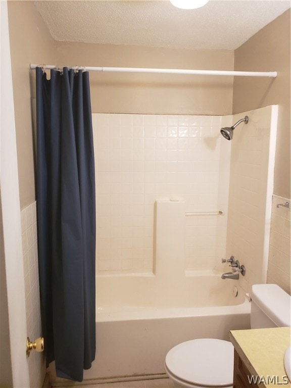 full bathroom featuring vanity, toilet, a textured ceiling, and shower / tub combo with curtain