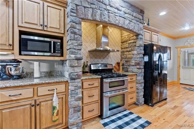 kitchen featuring crown molding, wall chimney exhaust hood, appliances with stainless steel finishes, tasteful backsplash, and light hardwood / wood-style floors