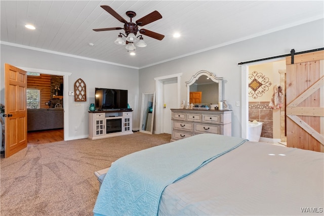 carpeted bedroom featuring a barn door, ensuite bath, ceiling fan, and ornamental molding