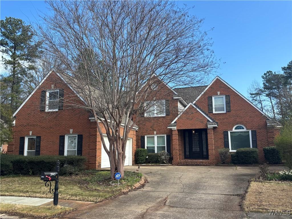 view of front of house with brick siding, an attached garage, and driveway