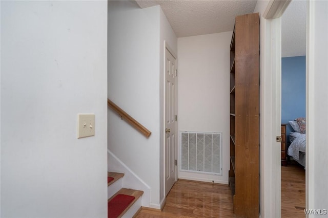 stairs featuring visible vents, a textured ceiling, and wood finished floors