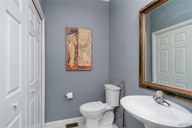 bathroom featuring tile patterned floors, visible vents, toilet, a sink, and baseboards