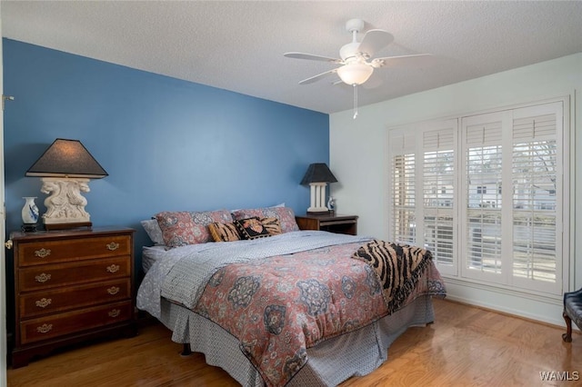 bedroom with ceiling fan, wood finished floors, and a textured ceiling