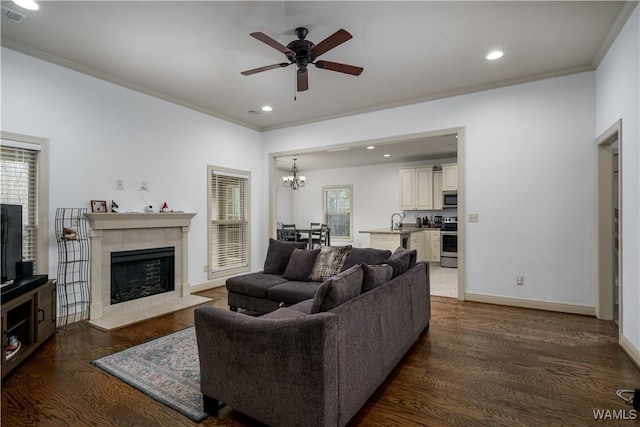 living room with a tile fireplace, dark hardwood / wood-style floors, sink, and ornamental molding