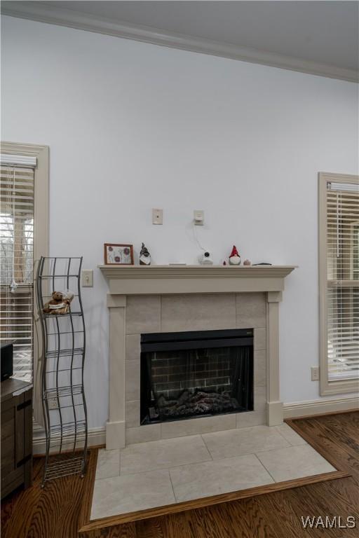 details featuring a tiled fireplace, wood-type flooring, and crown molding