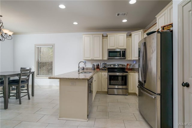 kitchen with sink, light stone counters, hanging light fixtures, stainless steel appliances, and cream cabinetry