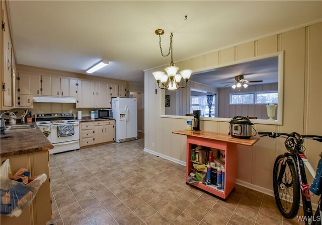 kitchen featuring pendant lighting, sink, white appliances, and ceiling fan with notable chandelier