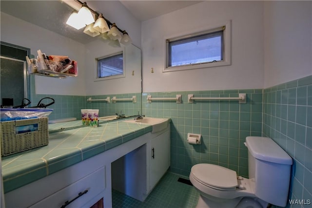 bathroom featuring tile patterned flooring, vanity, tile walls, and toilet