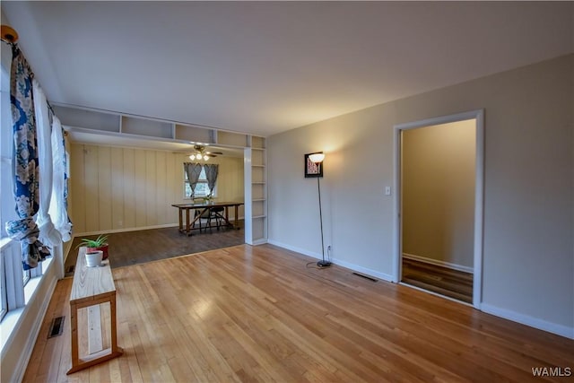 unfurnished living room featuring hardwood / wood-style flooring, built in features, and ceiling fan