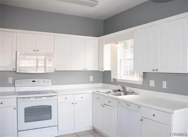 kitchen featuring sink, white cabinets, light tile patterned flooring, and white appliances